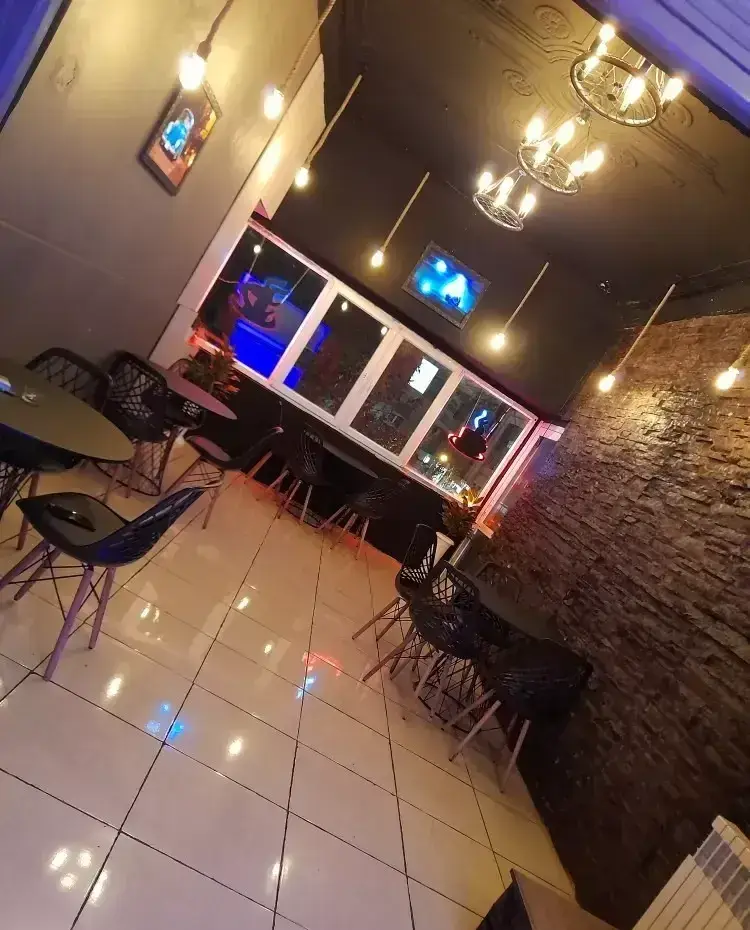 فضای داخلی شیک کافه قلیان عربی A&M با دکوراسیون مدرن، میز و صندلی‌های جذاب، نورپردازی خاص و دیوار آجری، محیطی دنج و ایده‌آل برای مشتریان.