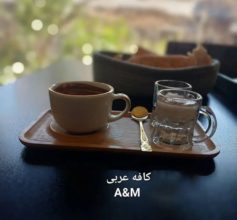 فنجان قهوه عربی و آب در سینی چوبی کافه قلیان عربی A&M، انتخابی ایده‌آل برای لذت بردن از نوشیدنی‌های سنتی و فضای دنج.