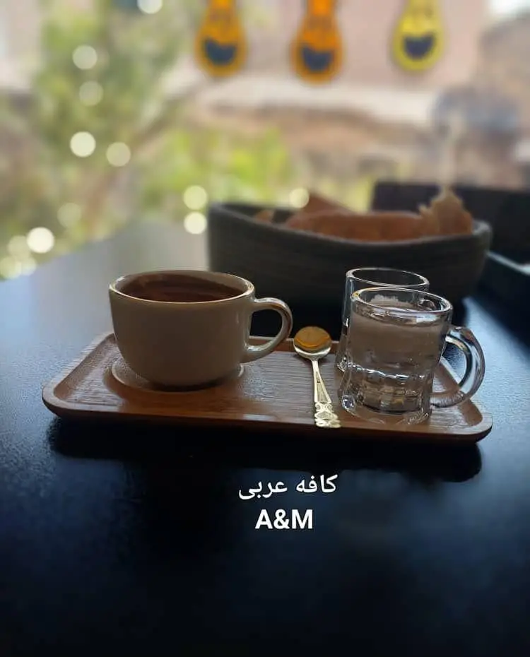 یک فنجان قهوه عربی سنتی، آب و قاشق روی سینی چوبی؛ فضایی آرام و دلنشین در کافه قلیان عربی A&M.