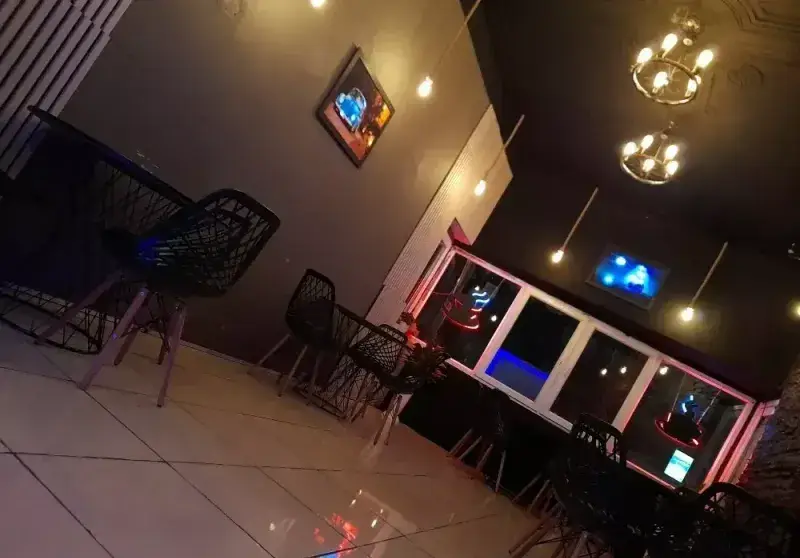 دکوراسیون داخلی کافه قلیان عربی A&M: میز و صندلی‌های مدرن مشکی، نورپردازی گرم و محیطی دنج و شیک ایده‌آل برای دورهمی‌ها.