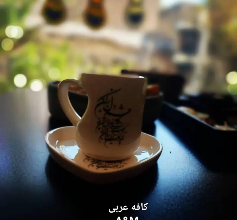 فنجان قهوه یا چای با خوشنویسی عربی زیبا در کافه قلیان عربی A&M، مکانی دنج برای اوقاتی دلنشین با دکوراسیون اصیل.