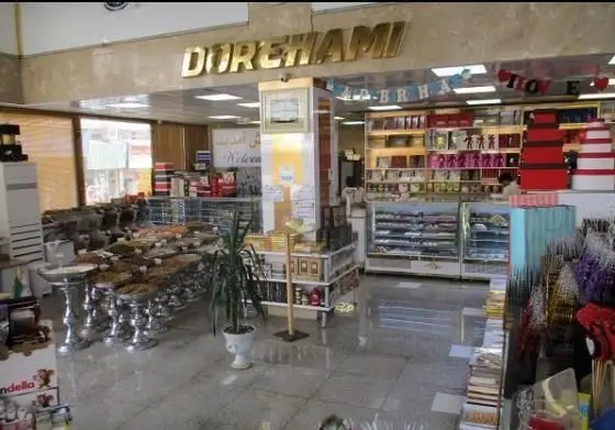 تصویری از داخل قنادی و شیرینی دورهمی، نمایشگر ویترین شیرینی‌ها، آجیل و خشکبار در ظروف زیبا و قفسه‌های محصولات متنوع و جذاب.