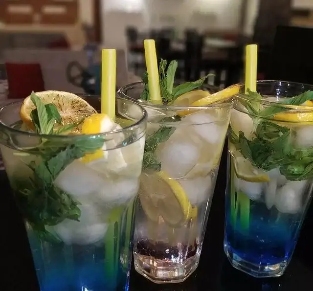 سه لیوان نوشیدنی خنک شامل موهیتو لیمو نعنا و نوشیدنی آبی، با یخ و نی زرد در کافه رستوران شهرزاد برای روزهای گرم.
