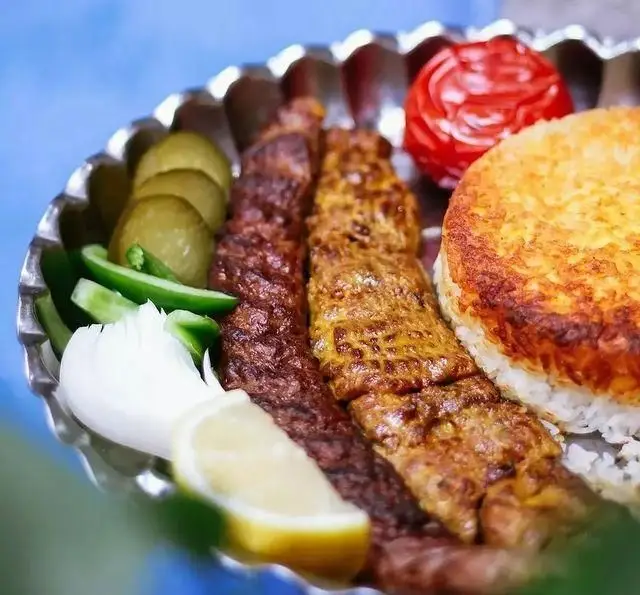 تصویری زیبا از کباب کوبیده و جوجه با ته دیگ برنج زعفرانی، گوجه کبابی، خیارشور، پیاز و لیموترش در کافه رستوران شهرزاد.