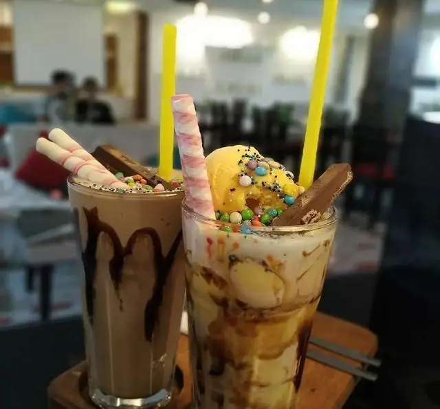 دو میلک شیک دلپذیر کافه رستوران شهرزاد: میلک شیک شکلاتی و وانیلی/میوه‌ای، با تزئین بستنی، آبنبات و ویفر برای تجربه‌ای خاص.