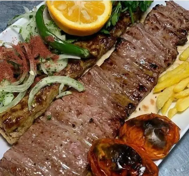 تصویری جذاب از کباب برگ و کوبیده کافه رستوران شهرزاد با مخلفات کامل شامل گوجه، سیب زمینی، پیاز و سماق، مناسب غذای ایرانی.