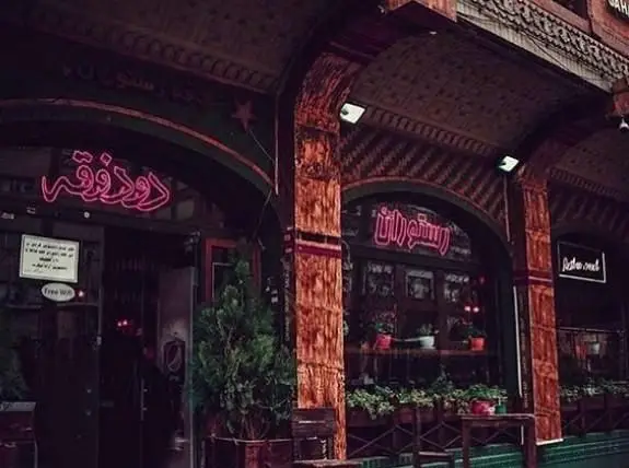 کافه رستوران دوذوقه، ورودی اصلی با تابلوی نئونی جذاب 'دوذوقه' و 'رستوران' در فضای شب و با امکان وای‌فای رایگان.