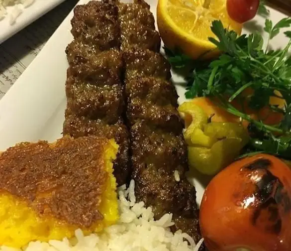 یک بشقاب چلوکباب کوبیده اشتهاآور کافه رستوران دوذوقه شامل دو سیخ کباب، برنج، ته دیگ طلایی و دورچین کامل. غذای ایرانی اصیل.