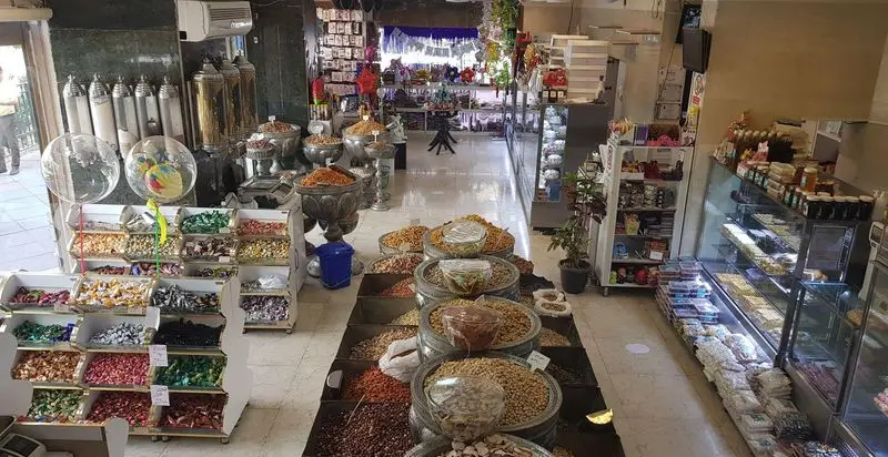 نمایی از داخل کافه قنادی بامداد با طیف گسترده‌ای از آجیل، خشکبار، شکلات‌های رنگارنگ و شیرینی‌های تازه و لذیذ. مکانی دلنشین برای خرید سوغات و تنقلات.