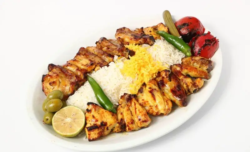غذای لذیذ تهیه غذای تایماز: جوجه کباب ایرانی با برنج زعفرانی، گوجه کبابی، زیتون، فلفل، خیارشور و لیمو. بهترین انتخاب برای سئو.