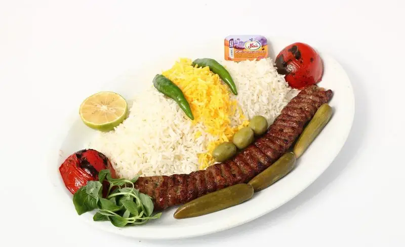 چلوکباب کوبیده تهیه غذای تایماز با برنج زعفرانی و سفید، گوجه کبابی، لیمو، زیتون، خیارشور و کره. غذای اصیل ایرانی برای سفارش.