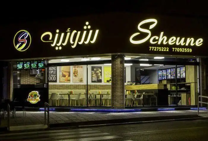 تصویری از نمای شبانه و تابلوی درخشان فست فود شورینه (Scheune) به همراه لوگو، شماره تلفن و طراحی داخلی مدرن رستوران.