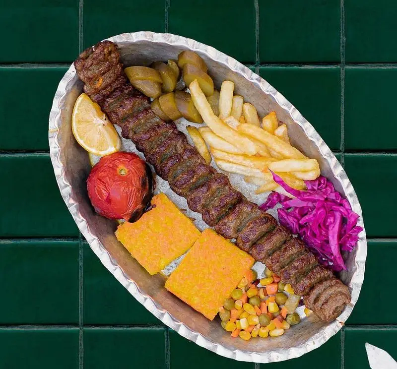 کباب کوبیده لذیذ رستوران سدره با سیب‌زمینی سرخ‌کرده، گوجه کبابی، خیارشور، ته دیگ زعفرانی و میکس سبزیجات