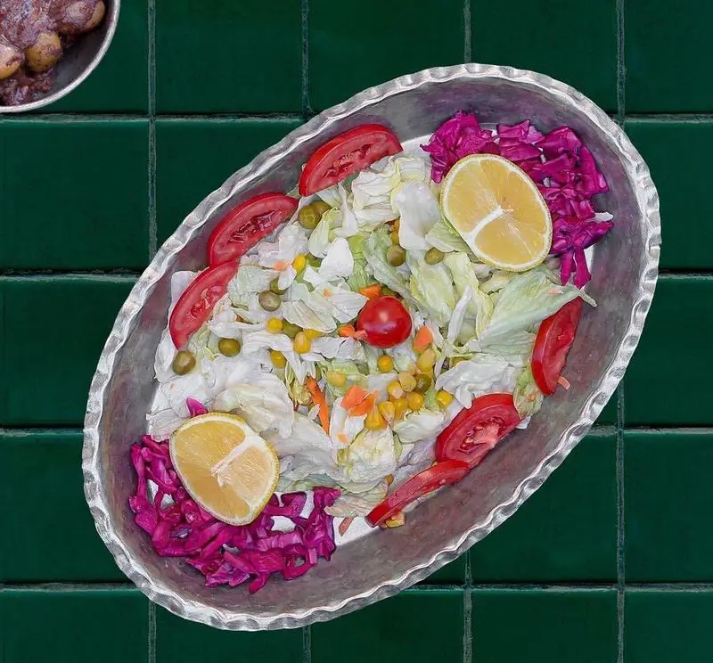 سالاد فصل تازه و اشتهاآور رستوران سدره شامل کاهو، گوجه‌فرنگی، کلم قرمز، ذرت، نخودفرنگی و برش‌های لیمو در ظرف فلزی سنتی.