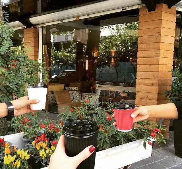 سه فنجان قهوه در دست مشتریان، نمادی از لحظات خوش در فضای باز دلنشین کافه رستوران داریما، محیطی ایده‌آل برای دورهمی‌های دوستانه.