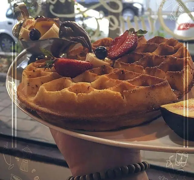 وافل طلایی و لذیذ کافه رستوران داریما با توت فرنگی تازه، موز، بلوبری و سس شکلاتی. یک دسر ایده‌آل برای صبحانه و عصرانه.