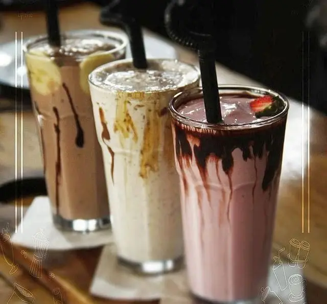 نمایی از سه میلک شیک رنگارنگ و خوشمزه (شیر موز، وانیل و توت فرنگی) با سس شکلات، تجربه ای خنک در کافه رستوران داریما.