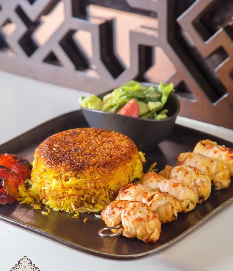 غذای خوشمزه از کافه رستوران عربی مدائن: چلو کباب مرغ با ته دیگ طلایی، همراه سالاد تازه. تجربه طعم اصیل غذای ایرانی و عربی.