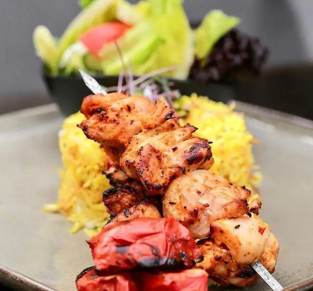 جوجه کباب آبدار و برشته با برنج زعفرانی و گوجه کبابی، یکی از غذاهای اصلی و محبوب کافه رستوران عربی مدائن.