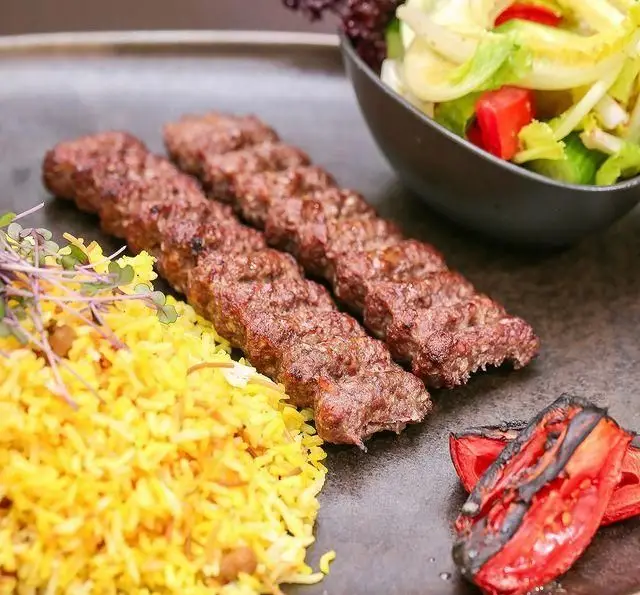کباب کوبیده خوشمزه به همراه برنج زعفرانی و سالاد تازه در کافه رستوران عربی مدائن. تجربه‌ای لذت‌بخش از غذای اصیل ایرانی و عربی.