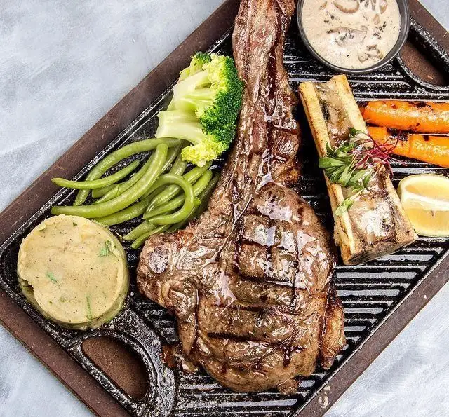 استیک لذیذ تاماهاک با سس قارچ، پوره سیب‌زمینی، مغز استخوان و سبزیجات تازه، منوی ویژه کافه رستوران عربی مدائن.