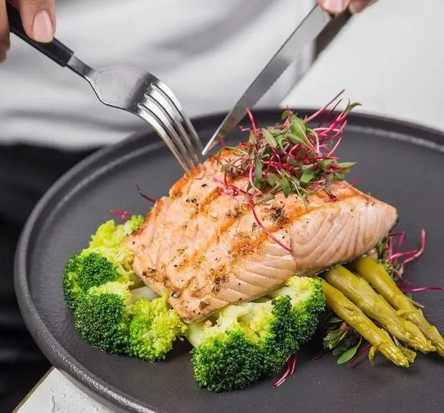 سالمون گریل شده آبدار و تازه همراه با بروکلی و مارچوبه بخارپز، یک غذای سالم و لذیذ در منوی کافه رستوران عربی مدائن برای ناهار و شام.