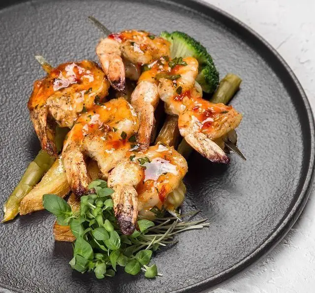 میگوهای گریل شده طعم‌دار با سس شیرین و تند، همراه با مارچوبه و بروکلی. تجربه‌ای لذیذ در کافه رستوران عربی مدائن.