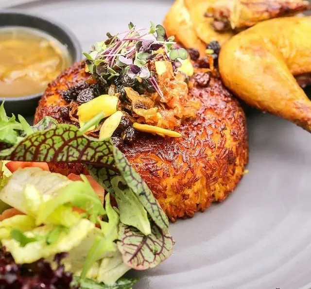 ته دیگ برشته زرشک پلو با مرغ خوش پخت و سالاد تازه کافه رستوران عربی مدائن، تجربه غذای اصیل و دلپذیر ایرانی.