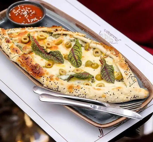 پیتزا قایقی پنیر و زیتون خوشمزه در کافه رستوران عربی مدائن؛ غذای مدیترانه ای با سس مخصوص و برگ های تازه.