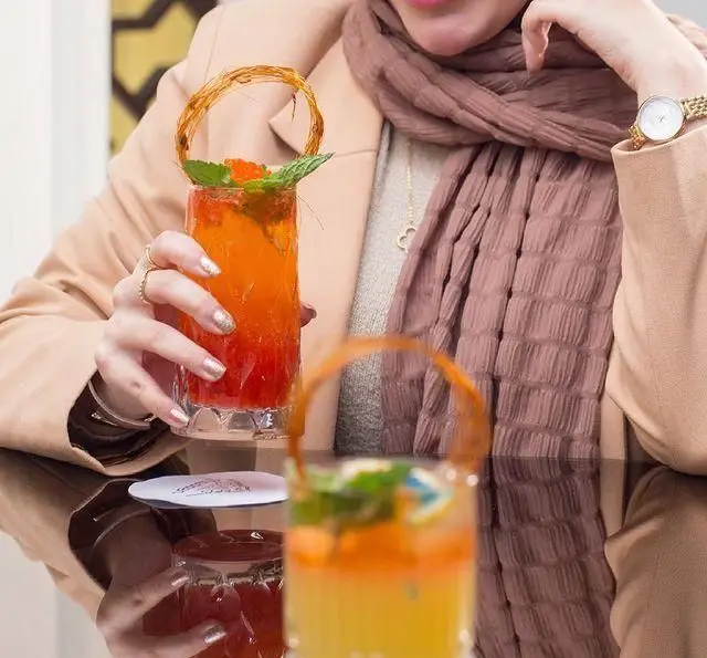 تجربه‌ای دلپذیر در کافه رستوران عربی مدائن: نوشیدن کوکتل میوه‌ای جذاب با تزیین هنرمندانه در فضایی با دکوراسیون شیک.