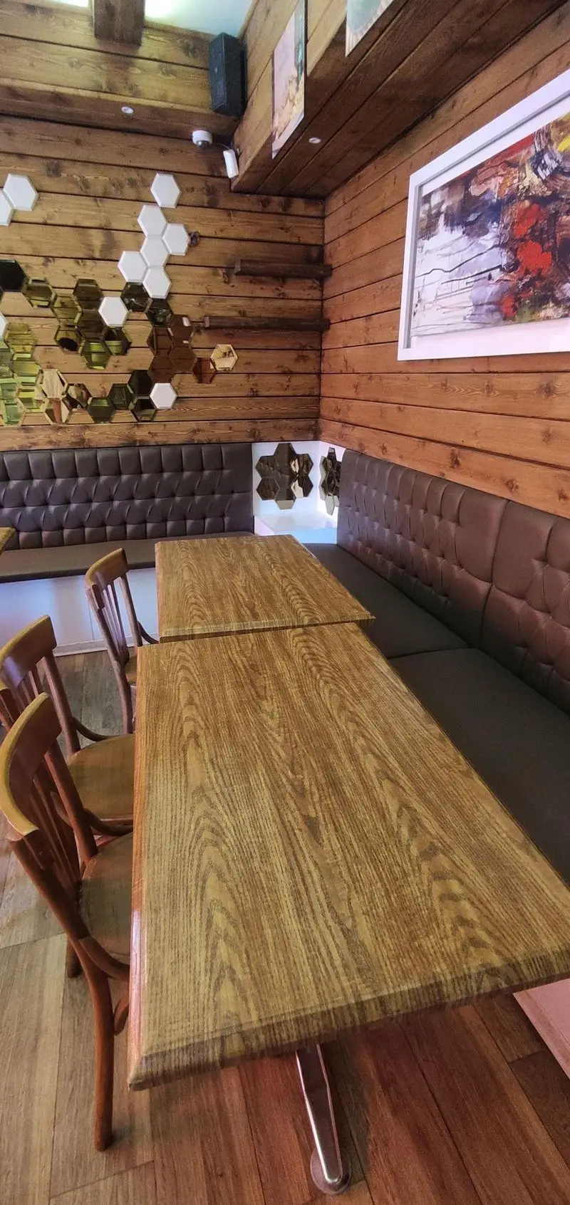 فضای داخلی دنج و مدرن فست فود دوراتو با دیوارهای چوبی روستیک، میز و صندلی‌های چوبی، مبلمان راحتی قهوه‌ای و آینه‌های دکوراتیو.