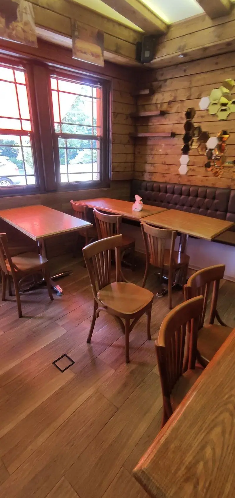 نمای داخلی دنج و چوبی فست فود دوراتو با میز، صندلی و کفپوش چوبی، پنجره‌های بزرگ و دیوارهای دکوراتیو با آینه‌های شش‌ضلعی.