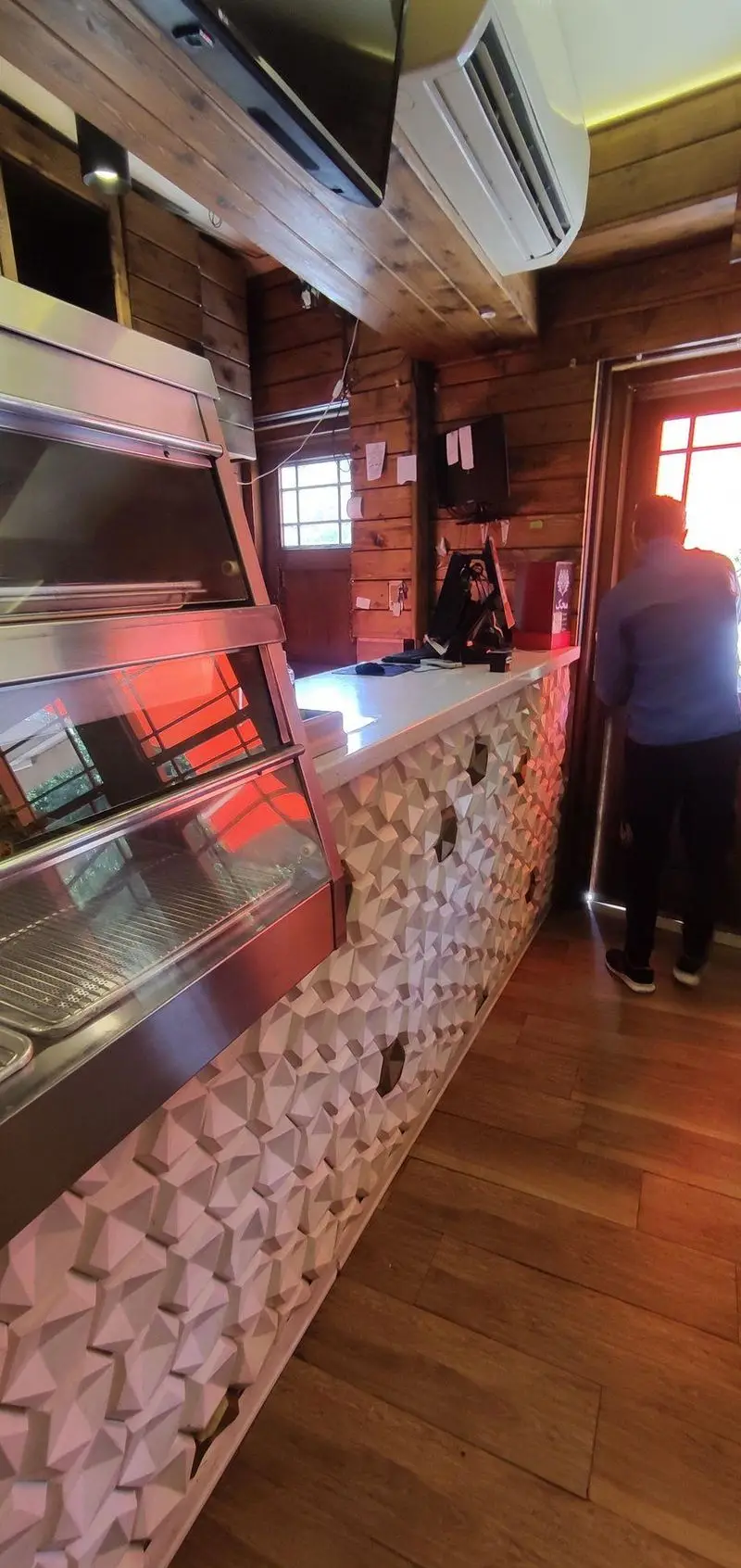 فضای داخلی فست فود دوراتو: پیشخوان مدرن سفید با طرح هندسی، ویترین نمایش غذا و دیوارهای چوبی گرم، محیطی شیک برای مشتریان.