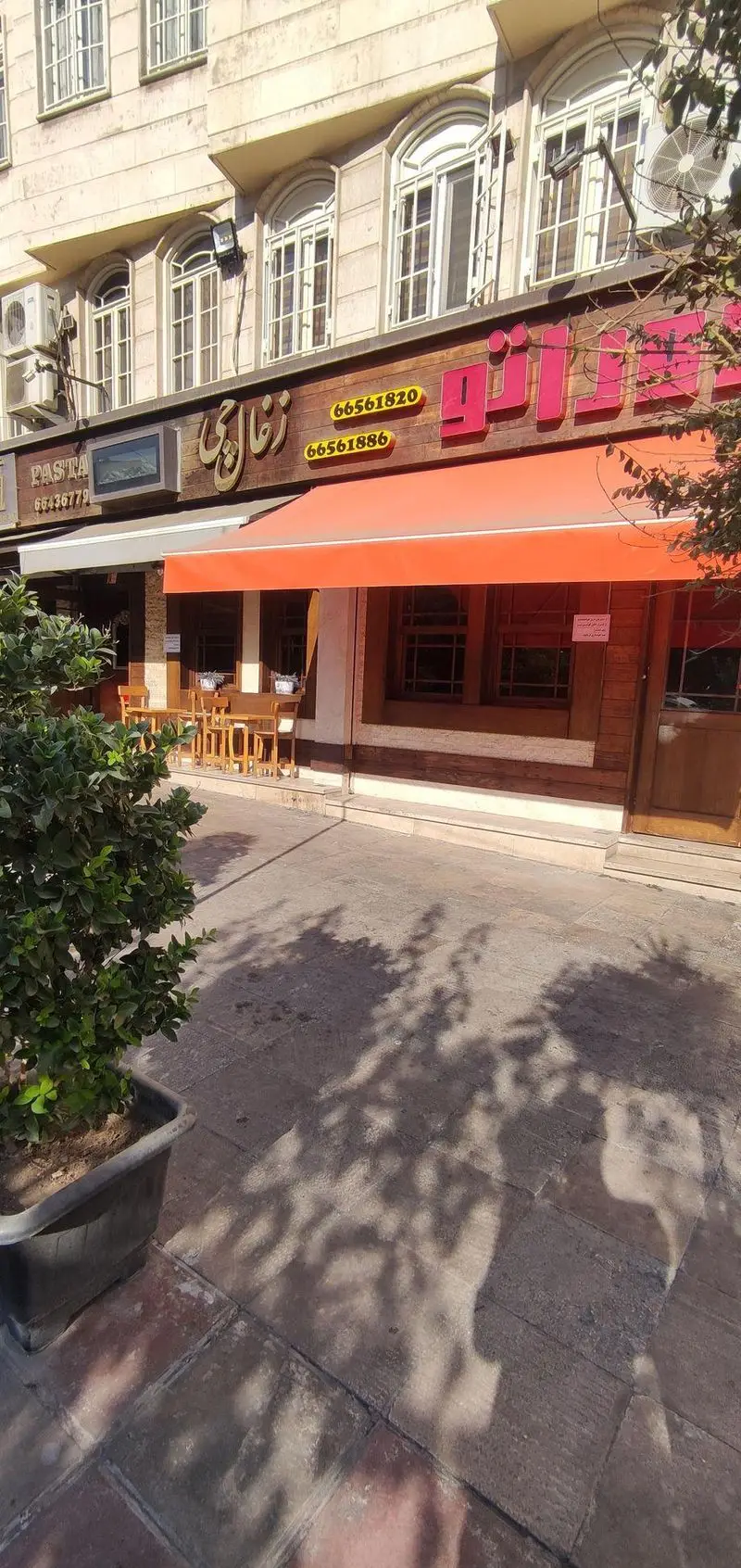 نمای خیابانی فست فود و ذغالی دوراتو با سایبان نارنجی، میز و صندلی فضای باز، تابلوی چوبی و شماره تماس 66561820 و 66561886.