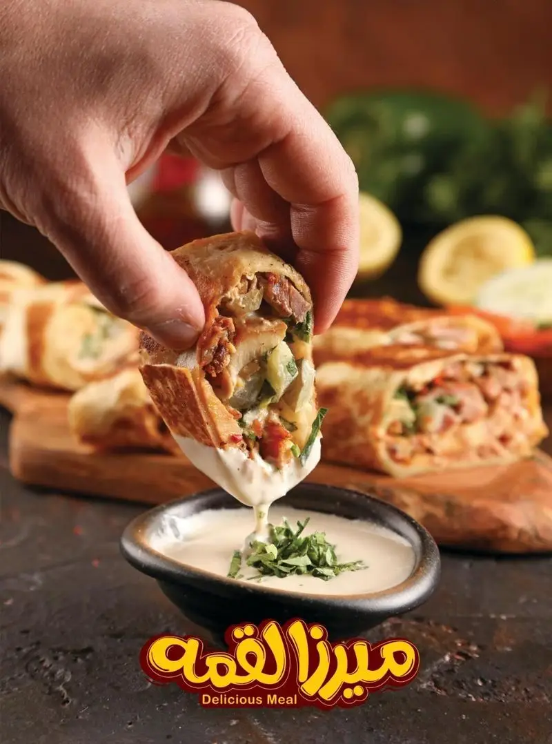 میرزالقمه: یک لقمه ساندویچ داغ و خوشمزه حاوی مرغ و گوشت، در حال دیپ شدن در سس سفید مخصوص، تجربه‌ای لذیذ از یک وعده غذایی کامل.