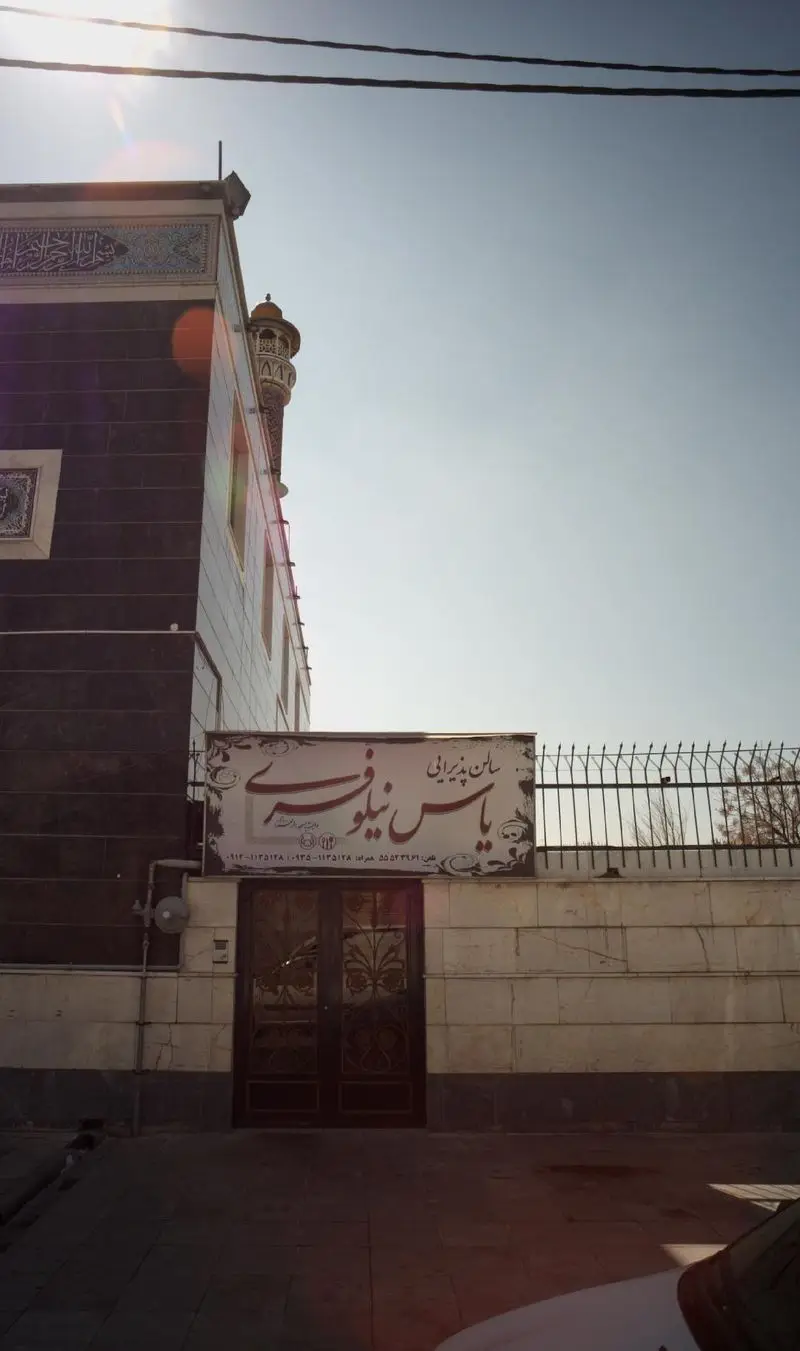 تصویر نمای بیرونی و تابلوی سالن پذیرایی یاس نیلوفری، مکانی زیبا برای برگزاری مراسم و رویدادها با معماری خاص.