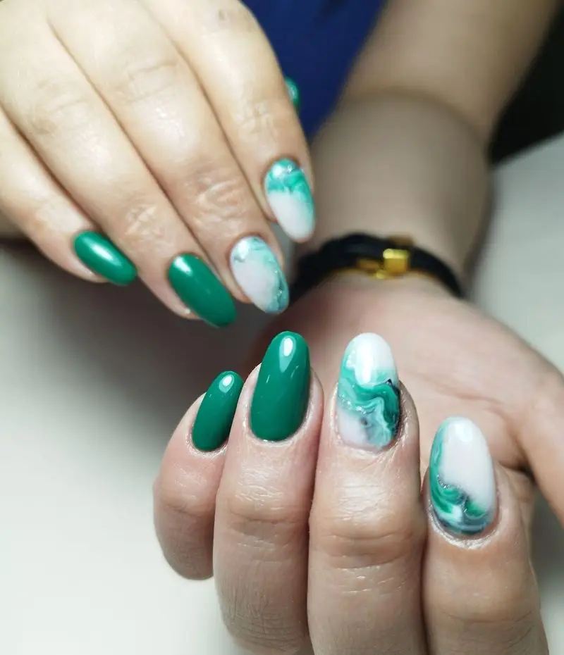 طراحی ناخن شیک با لاک ژل سبز زمردی و طرح مرمری سفید سبز به همراه اکلیل نقرهای، مناسب برای کاشت ناخن دخترانه جدید