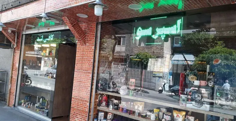 تصویری از نمای بیرونی و ویترین مغازه قهوه کافی لند، با نمایش انواع قهوه، دستگاه و فنجان‌های قهوه برای علاقه‌مندان به قهوه.