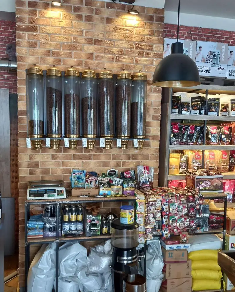 نمای کامل فروشگاه قهوه کافی لند با دیسپنسرهای دانه قهوه تازه، محصولات متنوع قهوه و اکسسوری، و آسیاب قهوه در فضایی مدرن.