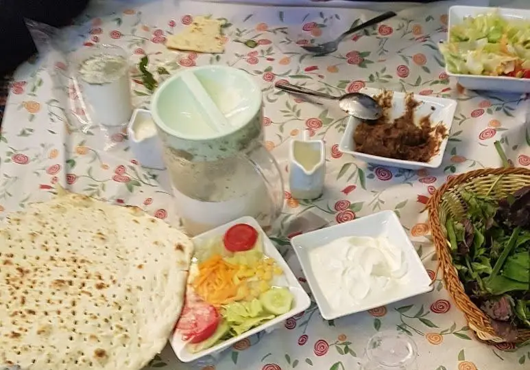 سفره شام کامل ایرانی در باغ رستوران نور: نان داغ، سبزی خوردن، ماست، سالاد و دیپ اصیل ایرانی.