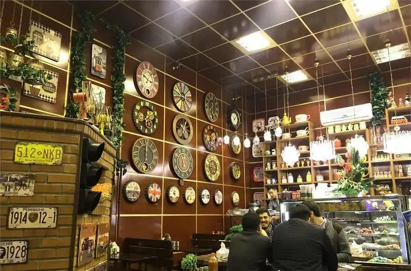 فضای داخلی دنج و دلنشین کبابی پامچال با دکوراسیون خاص و مجموعه‌ای از ساعت‌های دیواری و پلاک‌های قدیمی، پذیرای مشتریان.