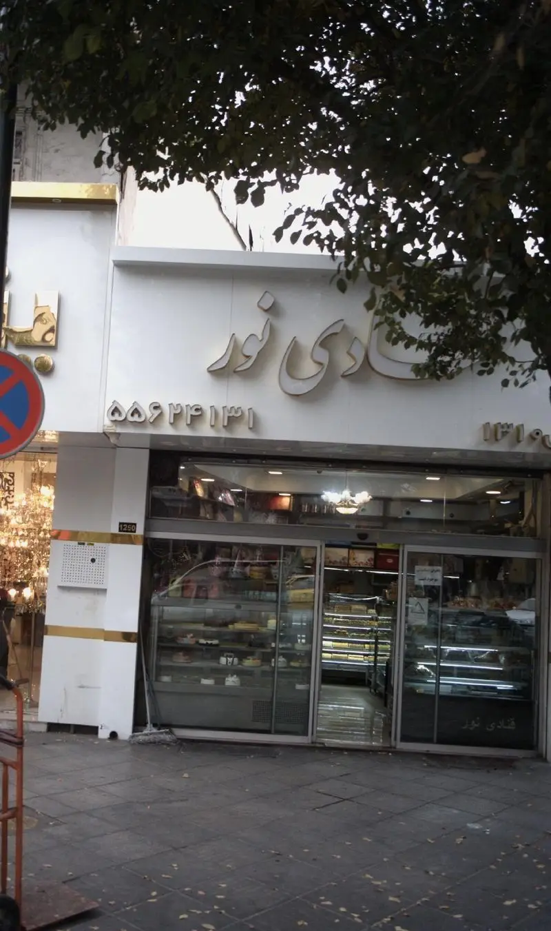 نمای بیرونی قنادی نور، یک شیرینی فروشی با ویترینهای پر از کیک و شیرینیهای تازه و خوشمزه، آماده پذیرایی از مشتریان.