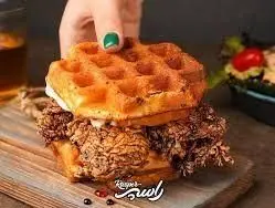 ساندویچ خوشمزه مرغ سوخاری و وافل از فست‌ فود سوخاری راسپر. مرغ کریسپی لذیذ بین دو وافل طلایی، انتخابی ایده‌آل برای غذایی متفاوت.