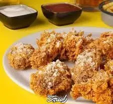 مرغ سوخاری کریسپی و طلایی فست‌ فود راسپر روی بشقاب سفید، با ادویه خاص و سس‌های خوشمزه. یک غذای آماده لذیذ.