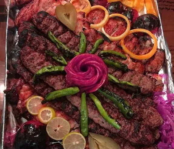 سینی مجلل و متنوع کباب‌های اصیل ایرانی کبابی خانه کباب: جوجه، کوبیده و برگ همراه با گوجه، فلفل، پیاز و لیمو تازه.