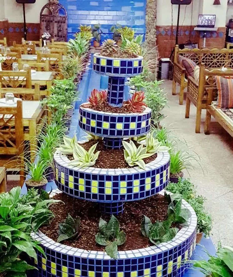 دکوراسیون زیبای سفره خانه سنتی زعفران با فلاورباکس طبقاتی کاشی‌کاری آبی و زرد، میز و صندلی چوبی و تخت‌های سنتی.