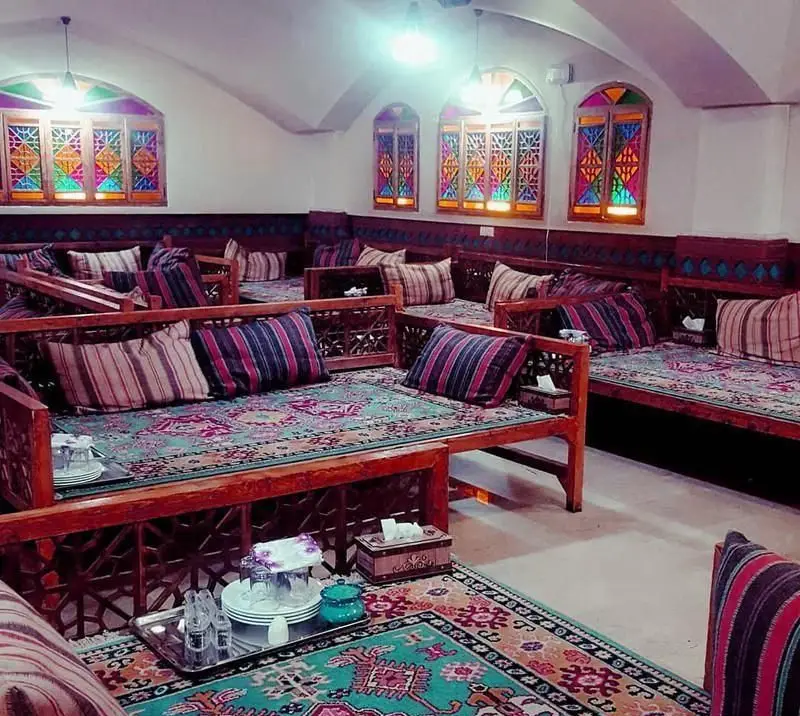 سفره خانه سنتی زعفران: فضایی آرام و دلنشین با دکوراسیون اصیل ایرانی، تخت‌های چوبی زیبا، فرش‌های دستباف و پنجره‌های ارسی رنگی.