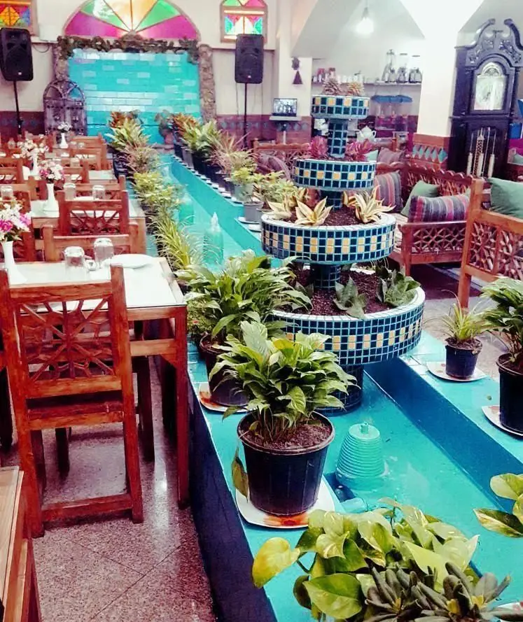 سفره خانه سنتی زعفران با دکوراسیون دلنشین ایرانی، حوضچه آب جاری و گلدان‌های طبیعی. محیطی آرام برای صرف غذا و چای.