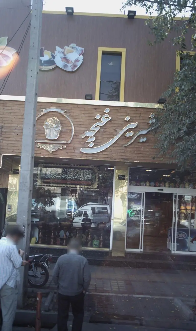 تصویر نمای بیرونی قنادی غنچه، یک شیرینی فروشی محبوب با تابلوی نئونی چشمگیر، ارائه دهنده انواع کیک، دسر و شیرینی.