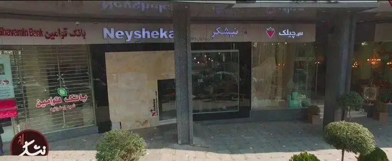 نمای بیرونی قنادی نیشکر شعبه زعفرانیه وی.آی.پی، واقع در خیابان، با تابلوی نیشکر روشن و ورودی مغازه شیرینی‌فروشی، کنار بانک قوامین.